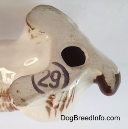 Close up - The underside of a brown and white ceramic Brittany Spaniel figurine. There is a stamp and a hole above the stamp on the underside of the figurine.