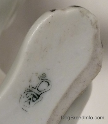 Close up - The underside of a white with brown Bulldog figurine. On the underside there is a logo of a Goebel crown trademark.