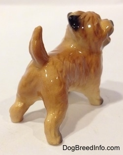 The back right side of a brown with black Cairn Terrier figurine. The figurien is glossy.