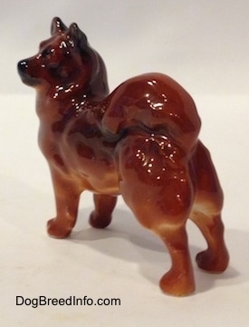 The back left side of a Chow Chow figurine that is in a standing pose. The figurine has a black muzzle.