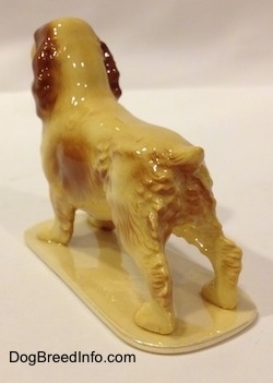 The back left side of a tan with brown ceramic Cocker Spaniel figurine. The figurine is very glossy.