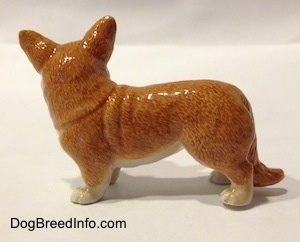 The left side of a brown with white porcelain Cardigan Welsh Corgi figurine in a standing pose. The figurine has white paws.