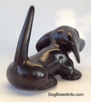 The back right side of a black Dachshund figurine. The figurine has a long body and big paws.