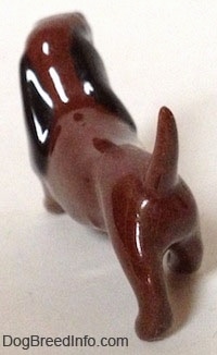 The back left side of a figurine that is of 'Dachsie' from 'Disney's The Lady and the Tramp'. The figurine is very glossy and its long tail is arched in the air.