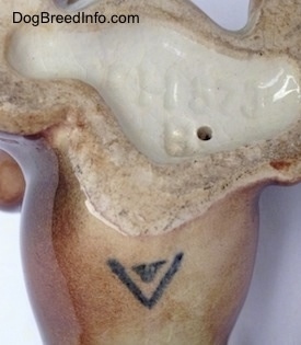 Close up - The underside of a Dachshund figurine. There is a logo and an engraving on the underside. The logo is the of Goebel W.Germany and the engraving reads - CH673B.