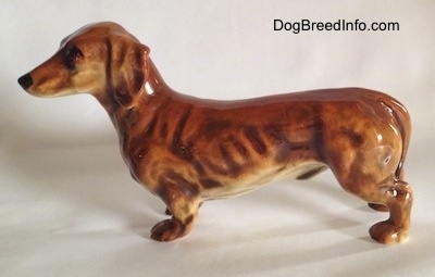The left side of a brown Dachshund figurine with great detail.