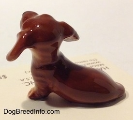 The left side of a Dachshund Puppy Seated Paw Up figurine. It is hard to differentiate the tail of the figurine from the body.