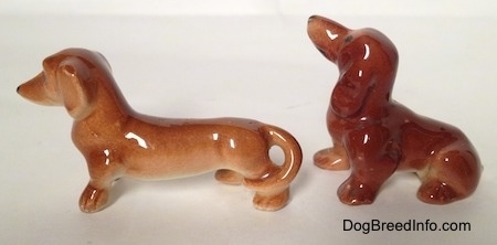 The left side of two different Dachshund figurines. The figurines have black circles for noses.