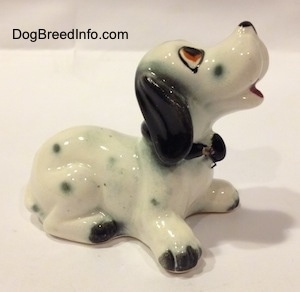 The right side of a Dalmatian puppy figurine. The figurine has a short tail and short appendages.