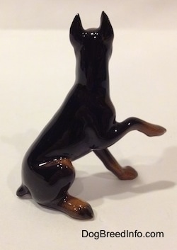 The right side of a figurine that is a black and brown Doberman Pinscher with its right paw up.