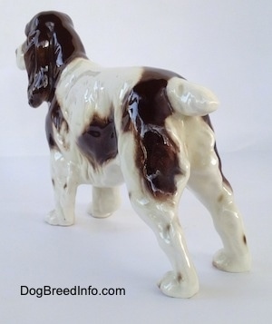 The back left side of a white with brown English Springer Spaniel figurine.