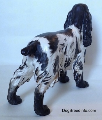 The back right side of a black and white English Springer Spaniel figurine with a matte finish. The tail of the figurine is sticking out and it is black.
