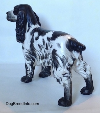 The back left side of a figurine of a black and white English Springer Spaniel figurine. The figurine has black paws.