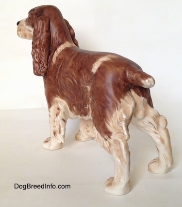 The back left side of a figurine of an English Springer Spaniel figurine in a standing pose with a matter finish. The trim of the figurine has hair around its leg and body edges.