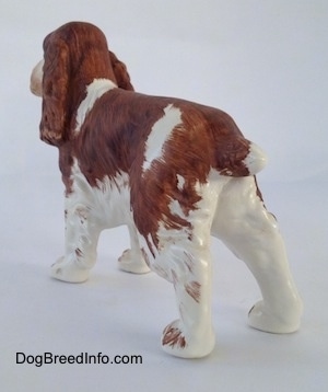 The back left side of a brown and white English Springer Spaniel figurine. The figurine has brown tipped paws.