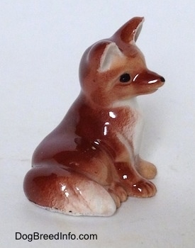 The back right side figurine of a baby Fox seated. The figurine has red detailed paws.