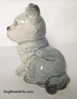 The back left side of a figurine of a French Bull Tzu. The figurine has black tipped ears and black tipped tails.