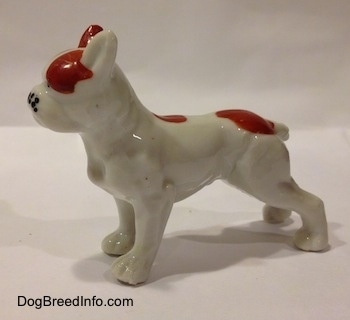 The left side of a bone china white with red bone French Bulldog figurine. The body of the figurine has fine details.