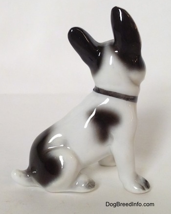 The right side of a white and black French Bulldog in a sitting pose figurine. The figurine has a black spot on its right side.