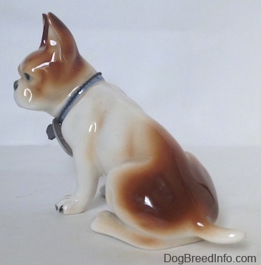 The back left side of a brown and white French Bulldog figurine. The figurine is glossy.