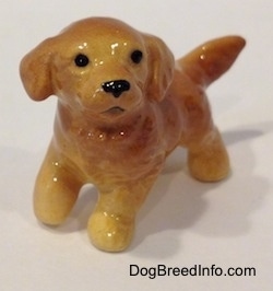A figurine of a Golden Retriever puppy that is glossy and it has no paw details.