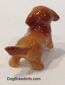The back right side of a figurine of a Golden Retriever puppy figurine. The figurine has down ears and it is hard to tell the difference between them and its head.