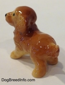 The back left side of a Golden Retriever puppy figurine. The figurines long tail is hard to differentiate from it body.