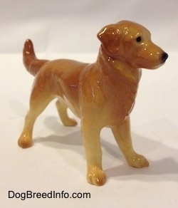 The front right side of a brown with tan Golden Retriever figurine. The figurine has long legs and small paws.