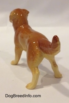 The back left side of a brown with tan Golden Retriever figurine. The figurine is glossy.