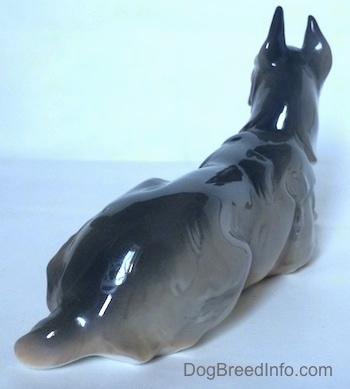 The back of a Great Dane laying down figurine that has a short tail.