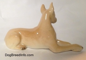 The right side of a tan Great Dane that is laying down figurine.