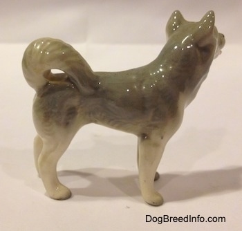 The right side of a grey and white Husky figurine. The figurine has small paws and they are black tipped.