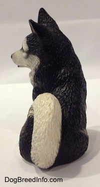 The back of a Husky figurine in a sitting postion that has its tail curled on to its back.