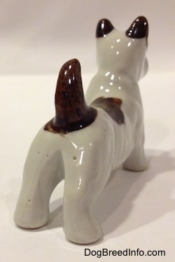 The back right side of a white with brown bone china Jack Russell Terrier dog figurine. The figurine has small brown ears.