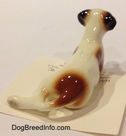 The back of a brown with white and black Jack Russell Terrier dog in a lying down pose. The figurine has a short tail.