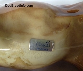 Close up - On the underside of a brown Labrador Retriever figurine that has a sticker on it.f