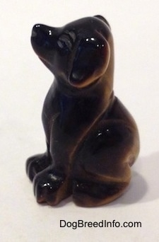 The left side of a Labrador Retriever figurine that is carved out of stone and its left side is black.