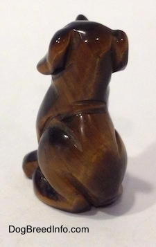 The back left side of a Labrador Retriever figurine that is carved out of stone. The figurine has no tail.