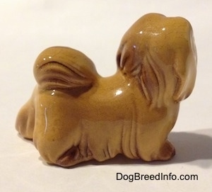 The right side of a figurine of a Lhasa Apso figurine. The figurine has hair hanging across its body.