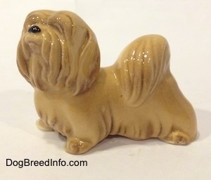 The left side of a tan Lhasa Apso figurine. The figurine has fine hair details.