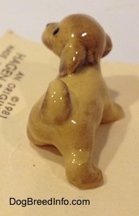 The back of a brown Lhasa Apso puppy figurine. The figurine is looking up and to the left.