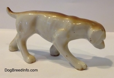 The right side of a figurine of a brown and white Lurcher that is sniffing. The figurine has long legs.