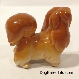 The right side of a brown with tan Pekingese puppy figurine. The figurine is glossy.