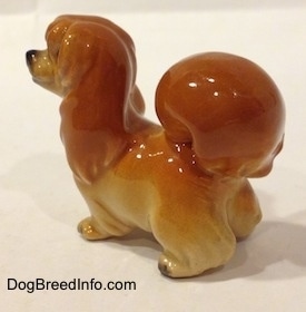 The back left side of a brown with tan figurine of a Pekingese puppy.