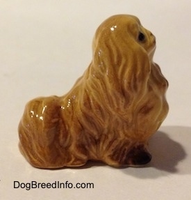 The right side of a tan Pekingese figurine. The figurine has short legs.