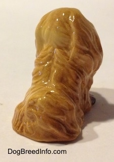The back of a figurine of a tan Pekingese. It is hard to differentiate the hair of the figurine from its head.