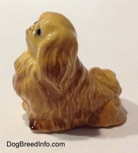 The left side of a tan Pekingese figurine.