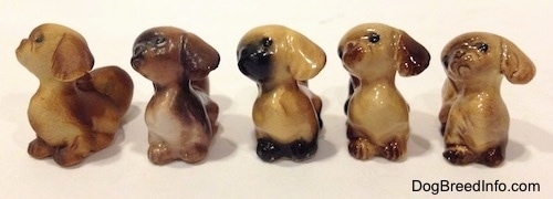 Five different color variations of a figurines of a Pekingese puppy seated figurine.