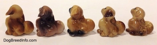The left side of five different figurines of a Pekingese puppy seated figurine. The figurines are glossy.