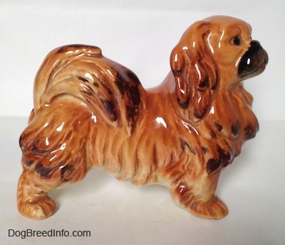 The right side of a brown and tan with black figurine of a Pekingese. The Pekingese has fine hair details.